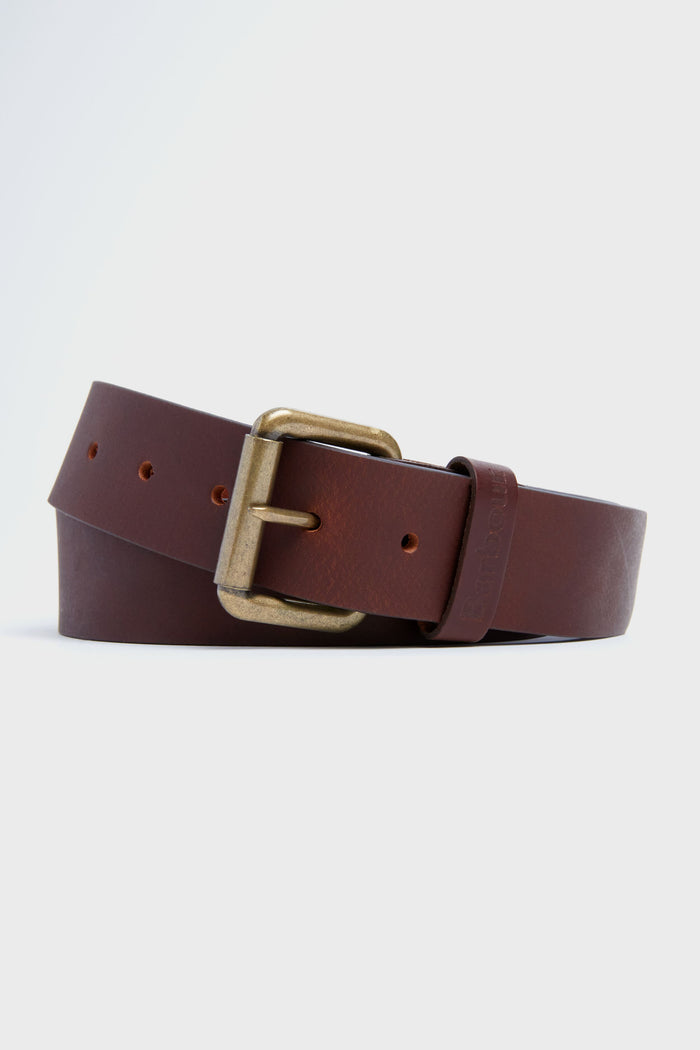 A Barbour leather belt, coiled to display its classic adjustable design and brass buckle, is shown in brown.