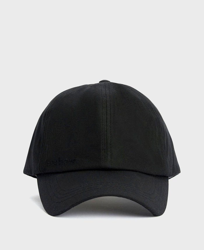 A Barbour black waxed cotton cap with a timeless look and water-resistant finish is displayed in a neutral, minimal setting.