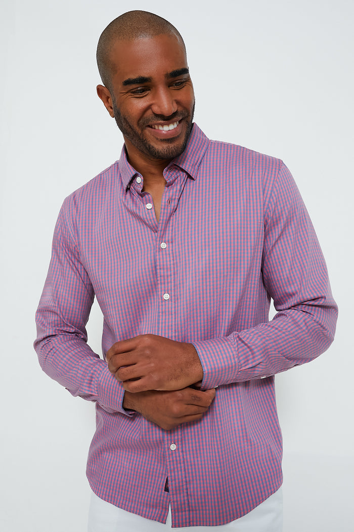 A man wearing a long-sleeve, button-up, pink and blue striped Supima cotton shirt from Faherty smiles and looks to the side.