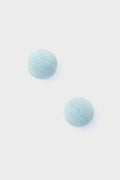 Two round, light blue, textured pieces from Tuckernuck Jewelry—reminiscent of Casey Studs or blue silk earrings—are artfully displayed.