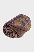 The Barbour rolled-up tartan dog blanket features a brown fleece side and a plaid patterned fabric on the reverse, offering cozy comfort for your pet.