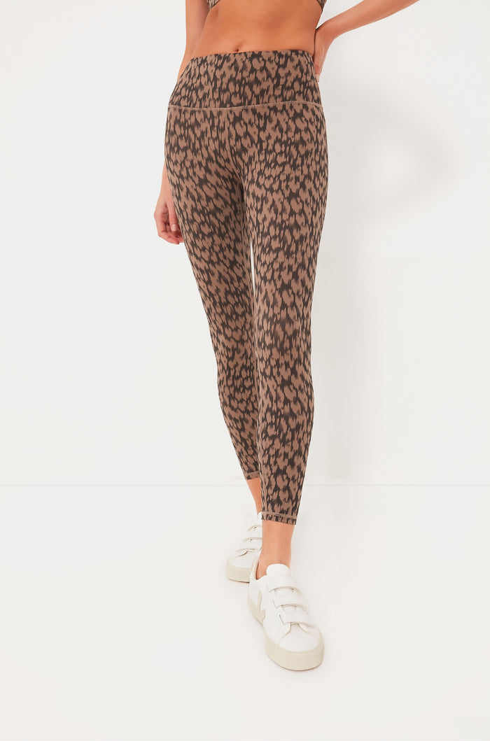 A person wearing Varley high-waisted brown and black leopard print leggings with white sneakers—perfect for an active lifestyle and featuring excellent moisture management.