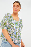 A woman models a stylish SZ Blockprints top with puffed sleeves and a floral block print, paired with light blue denim jeans.