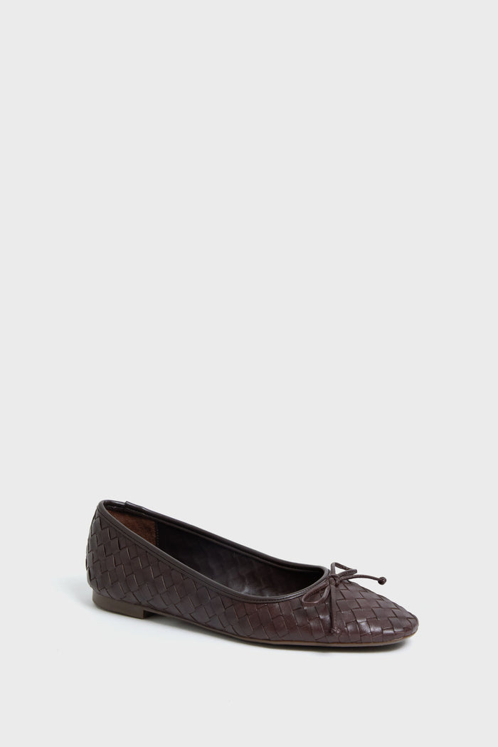 A Schutz ballet flat in dark brown woven leather, featuring a square toe and a small bow, is simply displayed.
