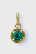 The Tuckernuck Fine Jewelry gold pendant features a round emerald charm at its center, crafted from 14k gold—an exquisite piece of luxury jewelry.