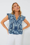 A woman wears a blue patterned Sea New York V-neck tank blouse with white pants, creating a chic and refined look.