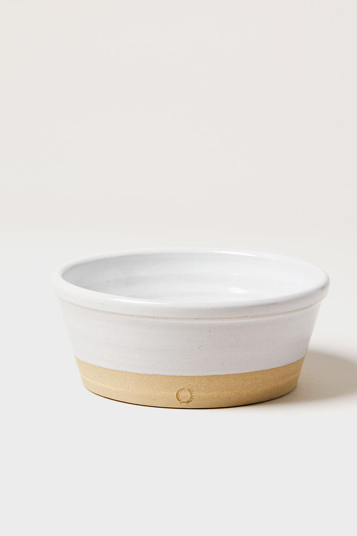A round ceramic bowl by Farmhouse Pottery, Inc with a white glazed upper half and an unglazed beige lower half, crafted in classic farmhouse style.