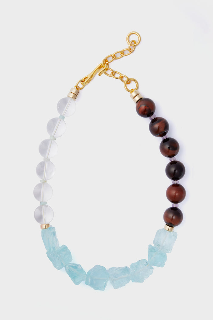 The Lizzie Fortunato necklace features alternating clear and brown round beads, irregular light blue stones, and is finished with a gold chain and clasp.