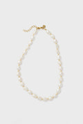 The Petit Moments freshwater pearl necklace features irregular white pearls, small gold beads, a gold clasp, and an adjustable chain for a perfect fit.