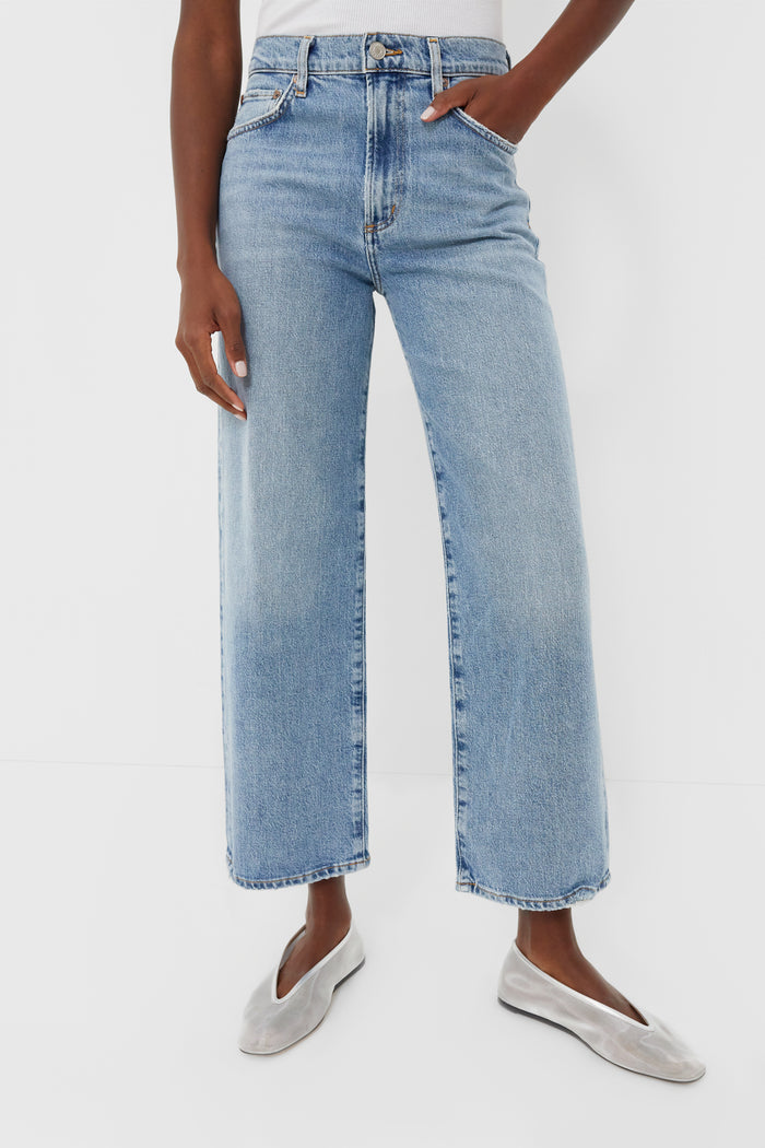 A person wears AGOLDE's light indigo, high-waisted wide-leg Harper Crop Jean with a white top and silver flats, highlighting the jean’s relaxed style.