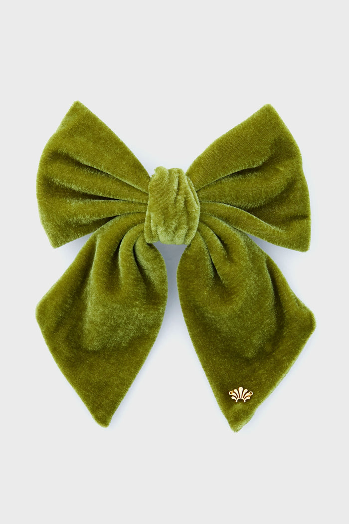 The Lele Sadoughi large green velvet bow features wide loops, flowing tails, and a small gold decorative emblem—an eye-catching statement accessory for hair enthusiasts.