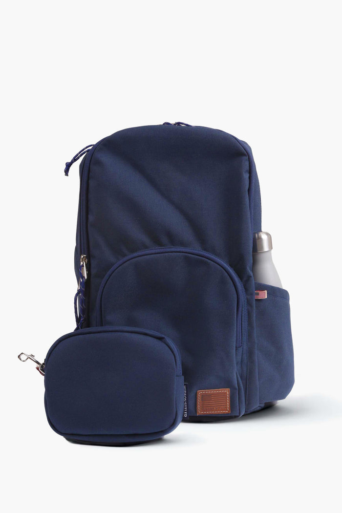 The Hudson Sutler navy blue backpack is ideal for daily use, featuring multiple zippered compartments, a side pocket for a metal water bottle, and a matching front pouch.
