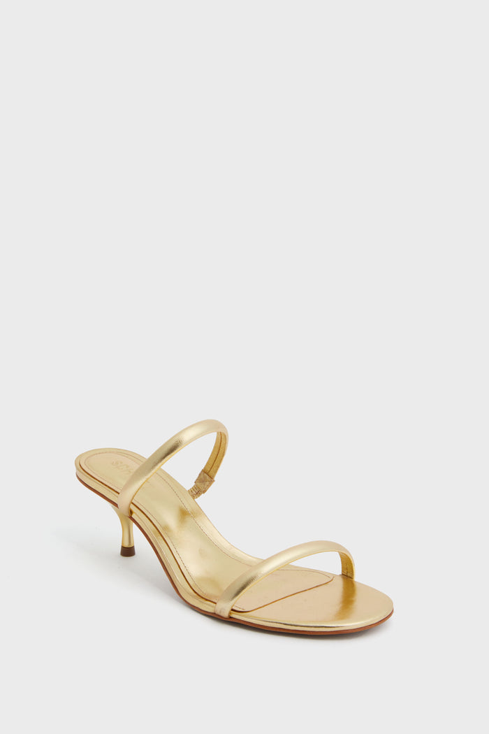 The Schutz gold heeled sandal features two thin straps, a low kitten heel, and an open toe. These slip-on leather heels offer elegance with their metallic gold finish.