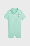 Light green cotton polo romper by Polo Ralph Lauren, featuring a collar, three buttons, and a small embroidered Polo Bear logo on the left chest—an iconic baby clothing piece.