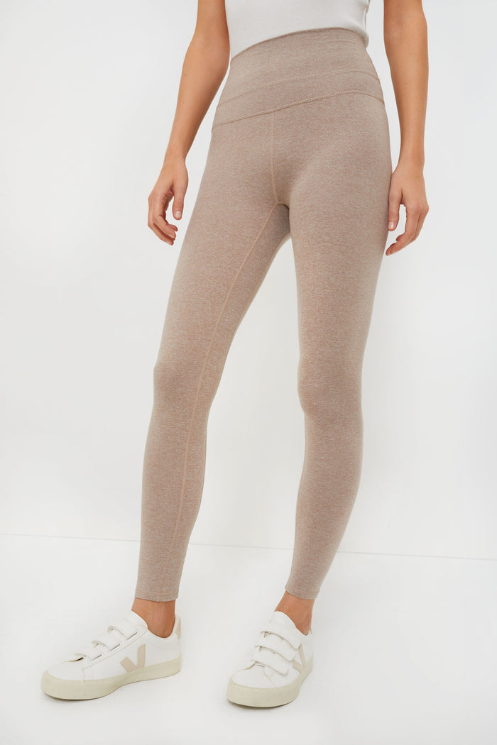 A person wearing high-waisted beige marled jersey leggings from Varley and white sneakers.