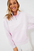 A woman wearing an Addison Bay pastel pink and white striped Varsity Quarter Zip pullover with white shorts smiles at the camera.
