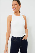 A woman wears a sleeveless white Veronica Beard Jordyn Tank with a racer-front design and dark blue jeans, smiling with one hand in her pocket.