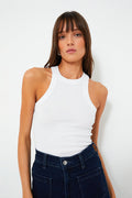A woman wears the Z SUPPLY White Lily Rib Tank, a sleeveless crewneck ribbed top, paired with high-waisted dark blue jeans.